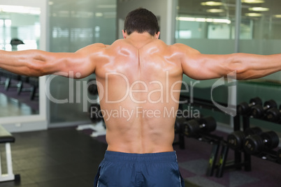 Bodybuilder with arms outstretched in gym