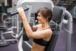 Happy brunette using weights machine for arms