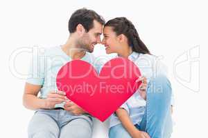 Cute couple sitting holding red heart