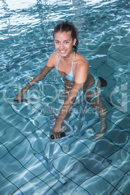 Fit brunette using underwater exercise bike