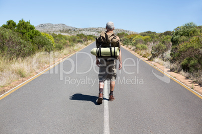 Handsome hiker walking on road and smiling at camera