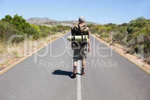 Handsome hiker walking on road and smiling at camera