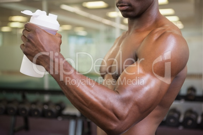 Sporty man holding protein drink in gym