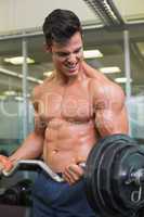 Shirtless muscular man lifting barbell in gym