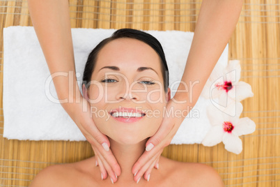 Smiling brunette enjoying a facial massage