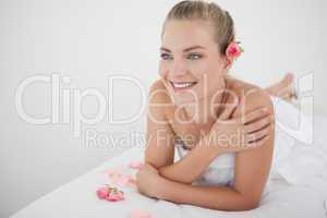 Pretty blonde lying on massage table with petals