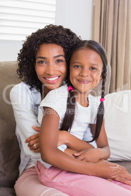 Pretty mother sitting on the couch with her daughter smiling at