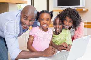 Cute siblings using laptop together with parents