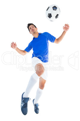 Football player in blue jumping to ball