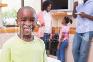 Cute little boy smiling at camera with family in background