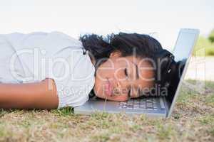 Casual pretty woman lying on the grass sleeping on her laptop