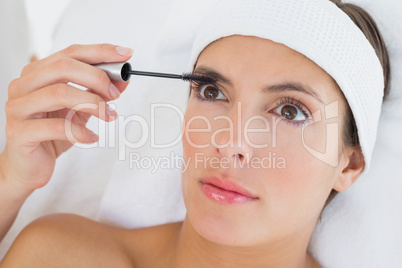 Hand applying mascara to beautiful woman