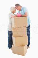 Older couple smiling at each other with moving boxes and piggy b