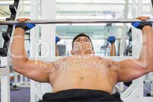 Shirtless muscular man lifting barbell