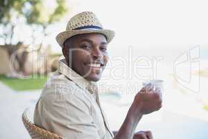 Smiling man relaxing in his garden having coffee