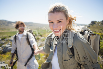Hiking couple standing on mountain terrain woman smiling at came
