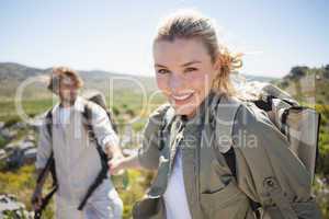 Hiking couple standing on mountain terrain woman smiling at came