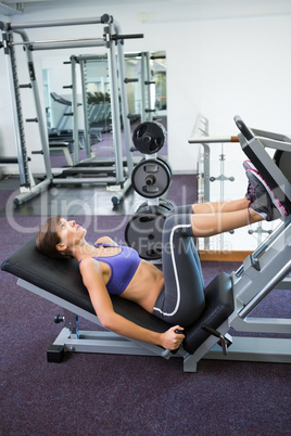Fit brunette using weights machine for legs