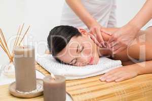 Beautiful brunette enjoying a shoulder massage smiling at camera