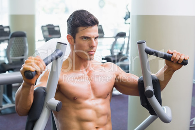 Muscular man working on fitness machine at the gym