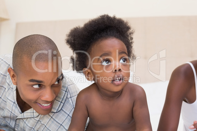 Happy couple sitting on bed with baby daughter