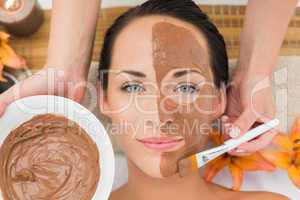 Peaceful brunette getting a mud facial applied