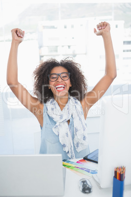 Pretty hipster cheering at her desk with laptop