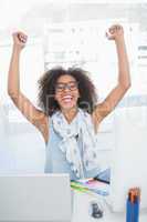 Pretty hipster cheering at her desk with laptop