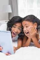 Surprised mother and daughter using tablet together