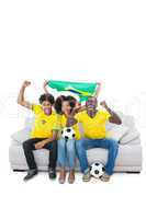 Brazilian football fans in yellow cheering on the sofa