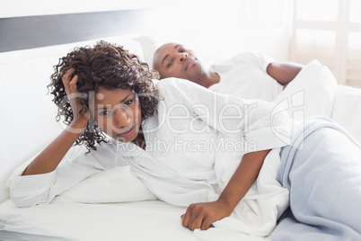 Annoyed woman lying in bed with boyfriend