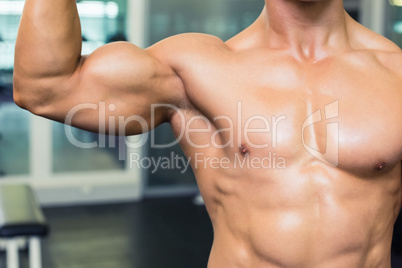 Mid section of a shirtless muscular man in gym