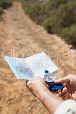 Hiker holding his compass and map in the countryside