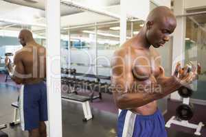 Serious shirtless young muscular man in gym