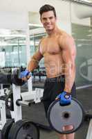 Shirtless muscular man lifting weight in gym