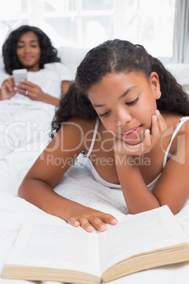 Happy mother and daughter relaxing on bed together