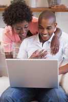 Happy couple relaxing together on the couch using laptop