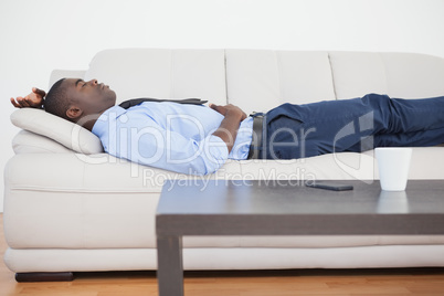 Tired businessman lying on the sofa