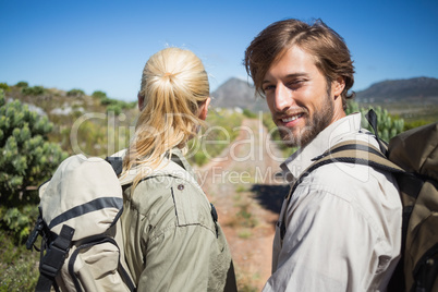 Hiking couple walking on mountain terrain man smiling at camera