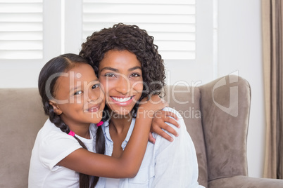 Pretty mother sitting on the couch with her daughter smiling at