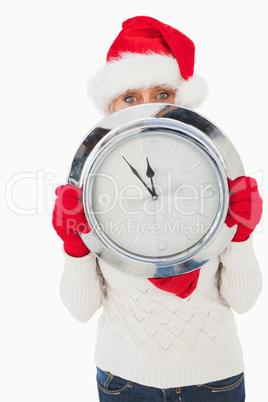 Festive woman looking at camera holding clock