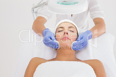 Hands cleaning womans face with cotton swabs