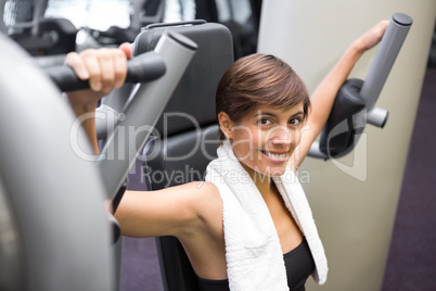 Happy brunette using weights machine for arms