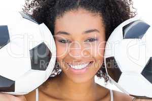 Pretty girl with afro hairstyle smiling at camera holding footba