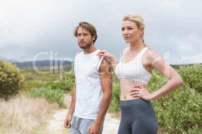 Attractive fit couple standing on mountain trail