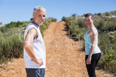 Fit smiling couple jogging up mountain trail