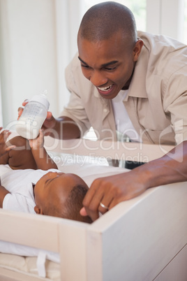 Happy father holding bottle for baby son
