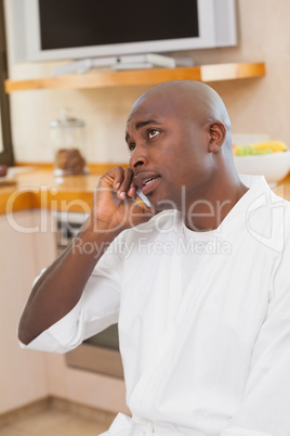 Serious man in bathrobe talking on phone