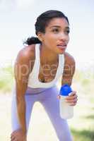 Fit woman holding sports bottle smiling