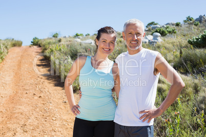 Fit smiling couple embracing and smiling at camera on country tr